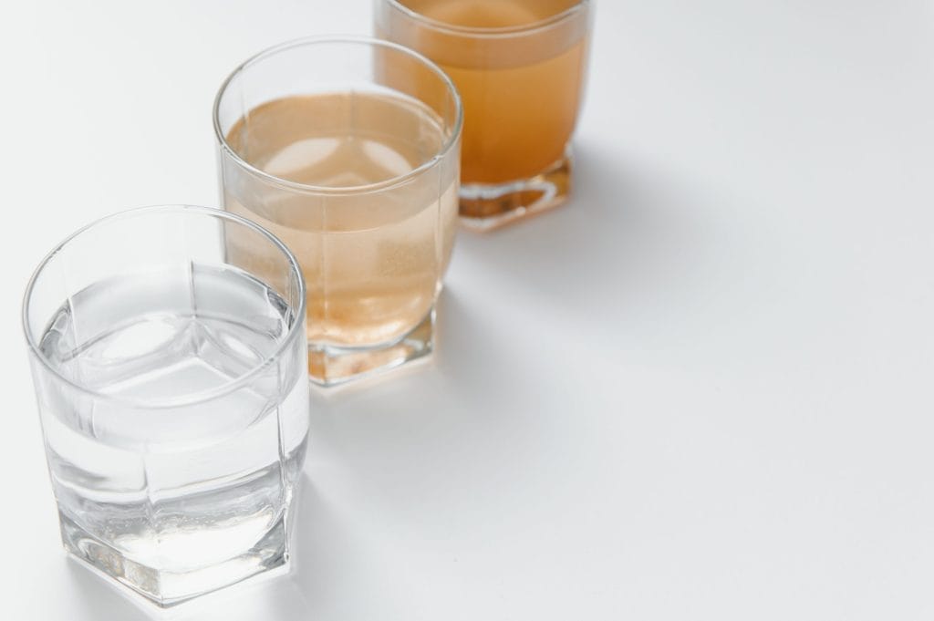 Three glasses showing stages of ferrous iron water test