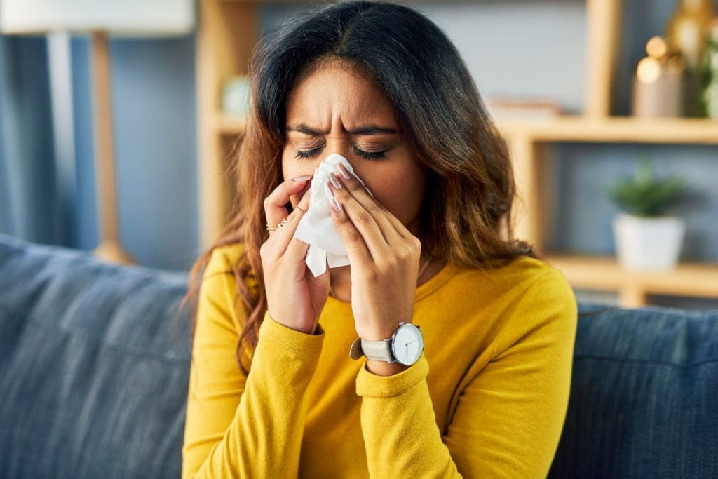 Woman sneezing indoors needing dust air testing service