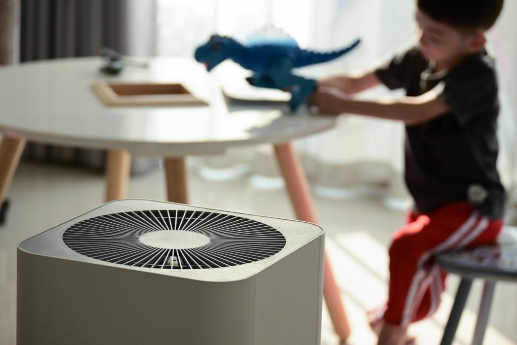 Child playing indoors with air purifier in focus