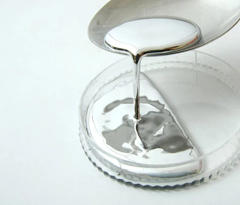 Mercury being poured from a spoon into a petri dish for water testing